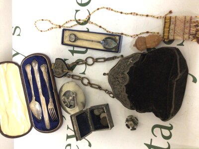 A collection oddments comprising a cased silver knife spoon and fork set an ornate purse a small seal and other oddments.