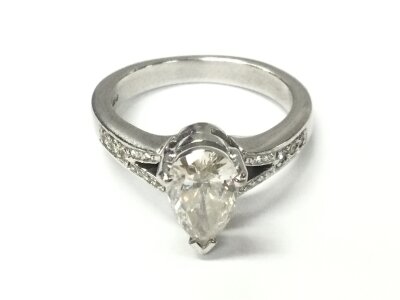 An 18ct white gold pear shaped diamond ring with diamonds set in shoulders. Size M and 6.70g. Pear shaped diamond is approximately 8.8mm by 5.5mm so roughly 1ct.
