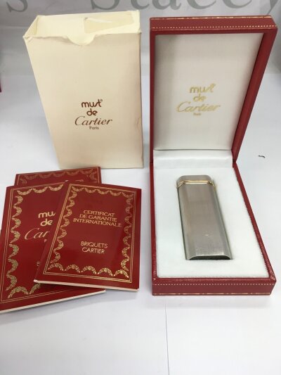 A boxed Cartier lighter with booklets.