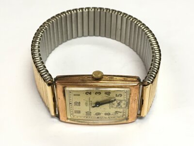 A gents gold watch with gold plated strap.