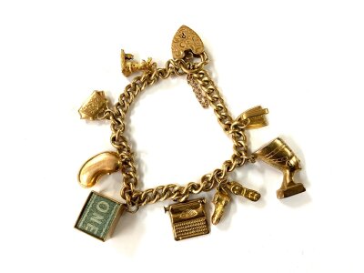 A 9ct gold charm bracelet set with multible 9ct gold charms and a 9ct gold cased £1 note charm.