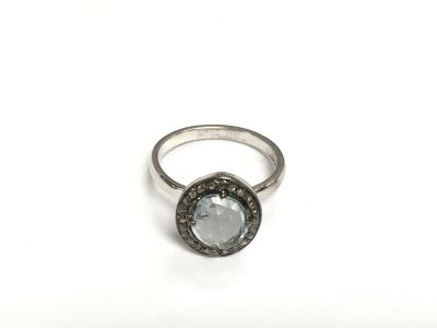 A white metal ring set with an oval checkerboard cut aquamarine and a halo of diamonds. Aquamarine approx 1.05ct, diamonds approx 0.15ct. Approx size N.
