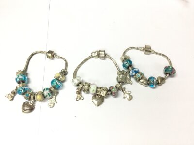 Three Pandora style charm bracelet with various charms.