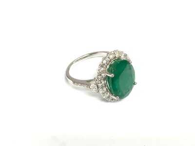 An 18ct white gold ring set with a large oval emerald and surrounded by RBC diamonds with trapezoid and RBC diamond shoulders. Emerald approx 6.86ct. Diamonds approx 1.25ct. Approx 5.5g and approx size N.