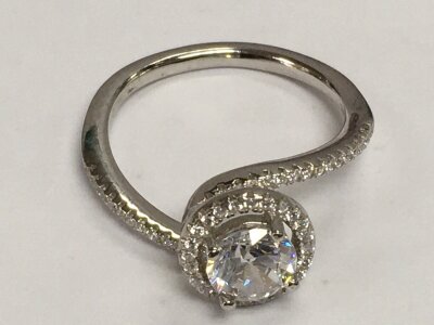 A silver cubic zirconia solitaire and halo ring set with further CZs on twist shoulders, approx size P-Q.
