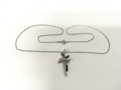 A silver double cross pendant set with white and black cubic zirconia on a silver chain.