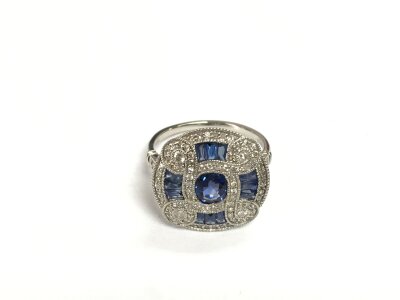 A platinum (950) fancy Art Deco style panel ring set with sapphires and diamonds. Centre oval sapphire approx 0.67ct, diamonds approx 0.47ct. Remaining calibre cut sapphires approx 0.38ct. Approx 5.8g and approx size N.