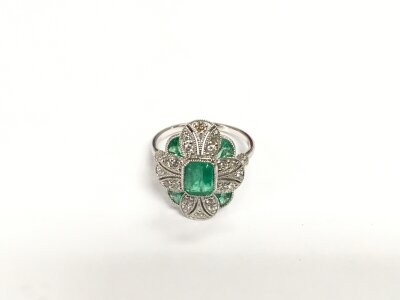 A platinum (950) Art Deco inspired ring set with step cut and calibre cut emeralds and eight cut diamonds with millegrain detailing. Emeralds approx 0.76ct, diamonds approx 0.32ct. Approx