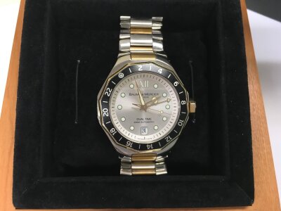 A boxed Baumé & Mercier automatic watch with champagne dial, date aperture and bi metal strap.
