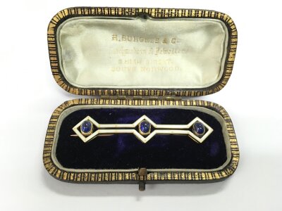 An Edwardian gold brooch set with three sapphire cabochons and enamel decoration, approx 5.9g.