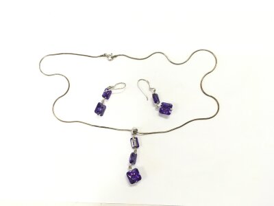 A silver necklace with purple stone pendant and a pair of matching earrings.