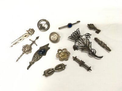 A collection of silver brooches.