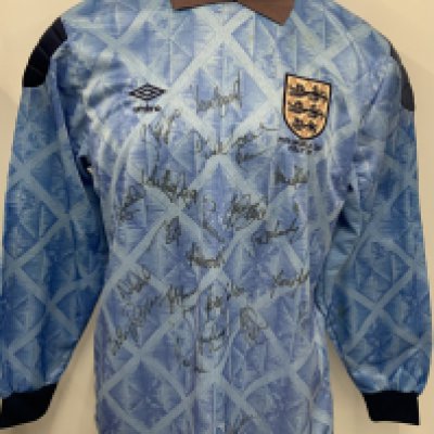 England 1990 World Cup Match Issued + Signed Football Shirt: Umbro XL long sleeve blue patterned goalkeepers shirt issued to Dave Beasant. The rear has number 22 in the correct felt dark blue numbering. The front has the stitched Umbro logo and under the 3 Lions badge are the words FIFA World Cup Italy 90. Signed by 23 which is probably the 22 man squad and Manager Bobby Robson. Usual fading to cloth collar and pull near the bottom near Peter Beardsleys autograph. Beasant was a late call up when Seaman got injured.