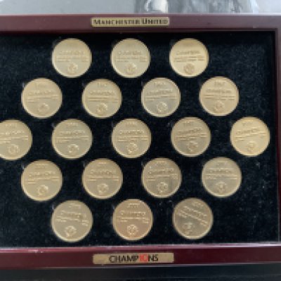 Manchester United League Champions Medals Framed Display: 19 large gold coloured medals each with the words Champions then a year that they were champions with how many points and who runners up were. Unglazed in a large photo frame.