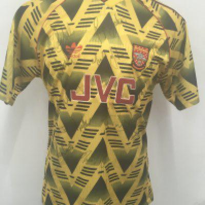 Arsenal 1991 - 1992 Merson Match Worn Bruised Banana Football Shirt: Stunning rare yellow patterned shirt known as the bruised banana and said to be the fans favourite ever kit. Number 10 to rear with Football League badging to arms in the last season before the Premier League. Short sleeve JVC sponsored shirt is signed to front by 13 including George Graham Kevin Campbell Alan Smith Paul Merson Lee Dixon Steve Bould John Lukic and many others.