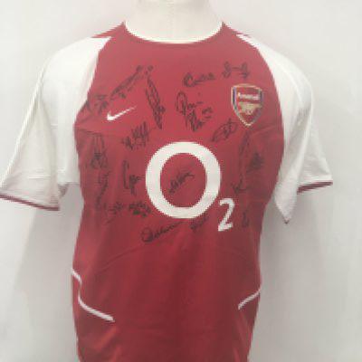 Arsenal Invincibles 2002 - 2004 Signed Football Shirt: Red short sleeve unused 02 sponsored large shirt. Signed to front by 19 players including Henry and Wiltord. Obtained by Paul Merson. Plenty of these about but rare to see a real one on kit mans shirt with inner mesh intact.