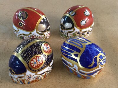 Four Royal Crown Derby paperweights in the form of beatles, including Scarrab Beatle - with damage.