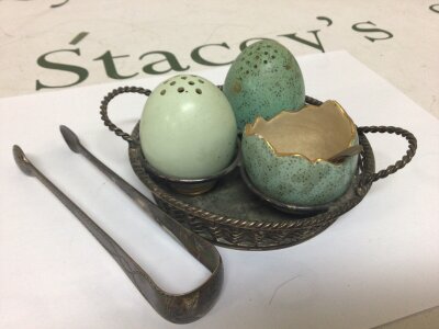 An unusual late 19th century Copeland ceramic condiment in the form of eggs in a silver plated basket and a pair of silver sugar tongs.