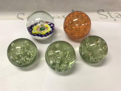 Five glass paperweights including three green bubble examples.