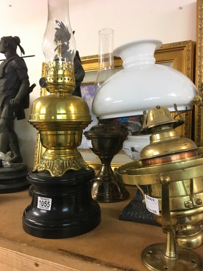 Four Oil lamps including a brass nautical style lamp , white shade oil lamp with floral decoration, brass lamps. Highest 61cm tall.