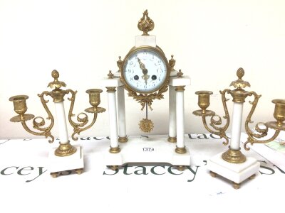 A late 19th century French Clock Garniture the clock with a brass movement striking on a bell with four white marble pillars with side ornaments gilt brass.