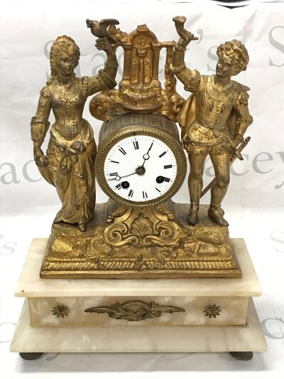 A French mantel clock featuring gilt figures and an alabaster base. Approximately 39cm tall 30cm wide