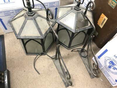 A pair of wrought iron lamps with some glass missing. 
70cm by 44cm approximately