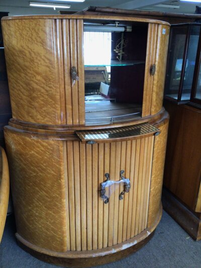 An Art Deco Burr Maple Cocktail cabinet of semi circular shape with sliding doors and mirrored interior.