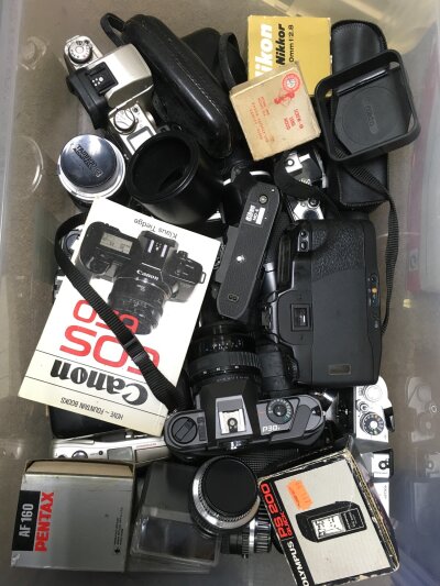 A box of mixed cameras and lenses.