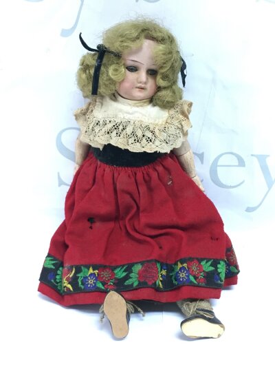 An early 20th Century bisque doll in traditional dress.