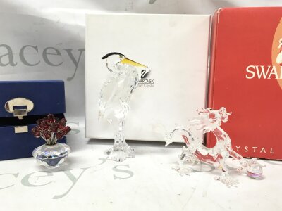 Boxed Swarovski crystal glass figures including silver heron, crystal vase of red roses, dragon (eye missing) with stand
