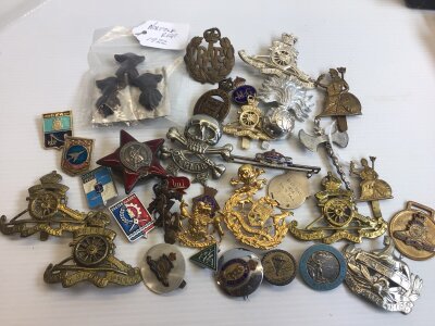 A collection of military badges mainly British and including a CCCP Russian badges a red enamel star. Silver and enamel 1937 Coronation badge.
