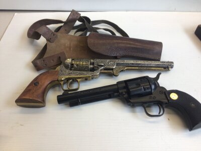 Two Replica Vintage revolvers non firing ornaments. With a leather holster.