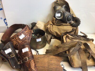 A collection of military accessories and leather gun holsters gas masks a German leather and canvas bag a collection of inert shells and war fragments and other oddments.
