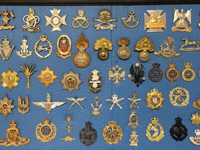 A Frame containing British Military hat badges of the second half of the 20th Century.