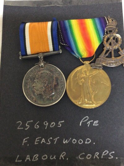 Two I world war medals awarded to 256905 Pte F Eastwood Labour Corps with a regimental cap badge.