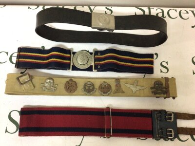 A Collection of Military belts A Russian belt and three British Military belts one mounted with a good selection of British military cap badges.