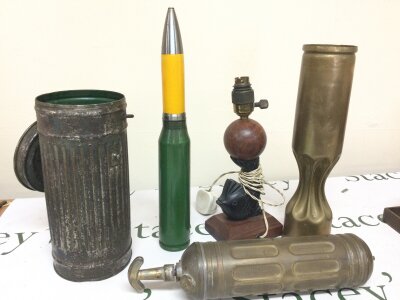 A collection of items including two caps, Brass Sprayer/Extinguisher, Gas Mask Container, deactivated 35mm auto-cannon round.