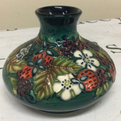 A Moorcroft vase decorated with raised fruit and flowers.