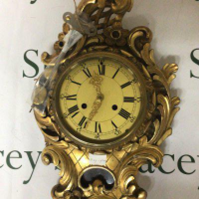 A Gilt wood Gesso wall clock of Rocco design with folate scrolls. With pendulum and key. 58cm