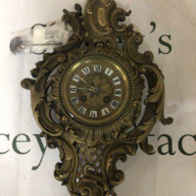A French brass early 20th century wall clock with elaborate scrolls with key and pendulum 48cm approximately.