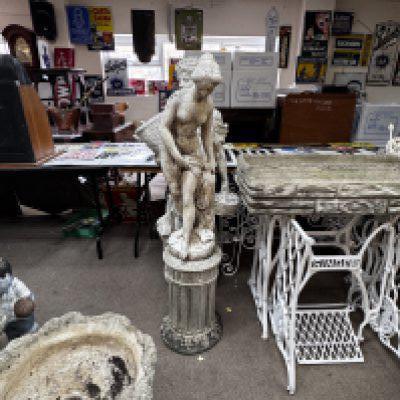 A cast concrete figure of a nude maiden, together with a plinth. Overall height. 131cm.