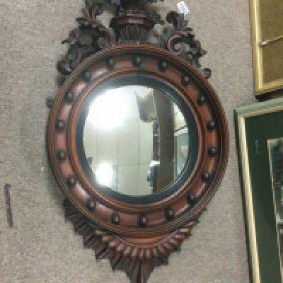 A profusely carved circular convex wall mirror surmounted by an eagle, approx height 93cm. Shipping category D.