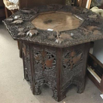 A profusely carved hardwood occasional table the hexagonal top with raised foliage height 58cm