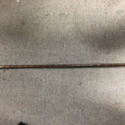 An antique walking stick with a metal cuff round the handle and stick.