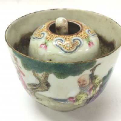 A Chinese Famille Justice cup containing a small figure of the Immortal of Longevity holding a peach stuck inside that rises when water is poured in the cup. Sides of the cup decorated with figures. 6.5cm tall 8cm wide . This lot cannot be posted