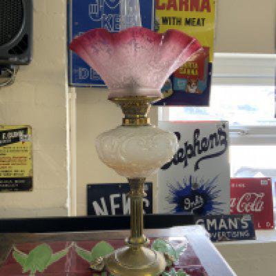 A Victorian brass column oil lamp with lion paw feet, opaline glass reservoir and faded etched cranberry shade.