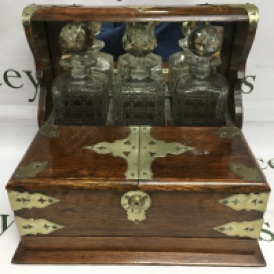 An oak tantalus with three bottles, no key but is open. Shipping category D.