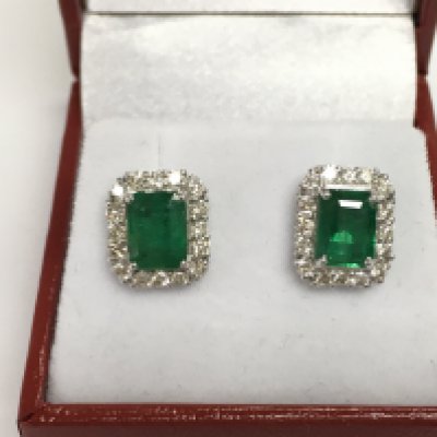 A pair of 18ct white gold studs set with step cut emeralds each surrounded by diamonds. Emeralds 2.92ct and diamonds 0.80ct approximately.