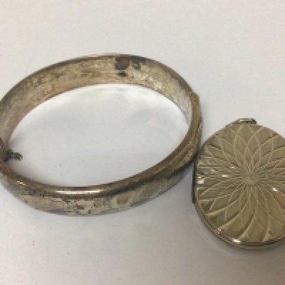 A Silver bangle and an oval Silver locket. (2)
